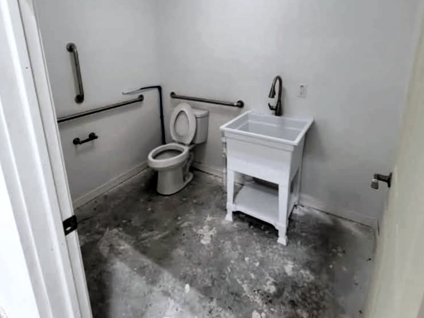 Private washroom inside a Flexbays unit with toilet, utility sink and grab bars